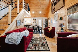 L’intérieur d’un chalet en bois comprend un escalier, des canapés rouges, un coin repas et une cuisine.
