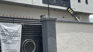 Un bâtiment moderne à la façade blanche, doté de nombreuses fenêtres et d’une banderole publicitaire pour « EXTRAVAGANZA STAY ».