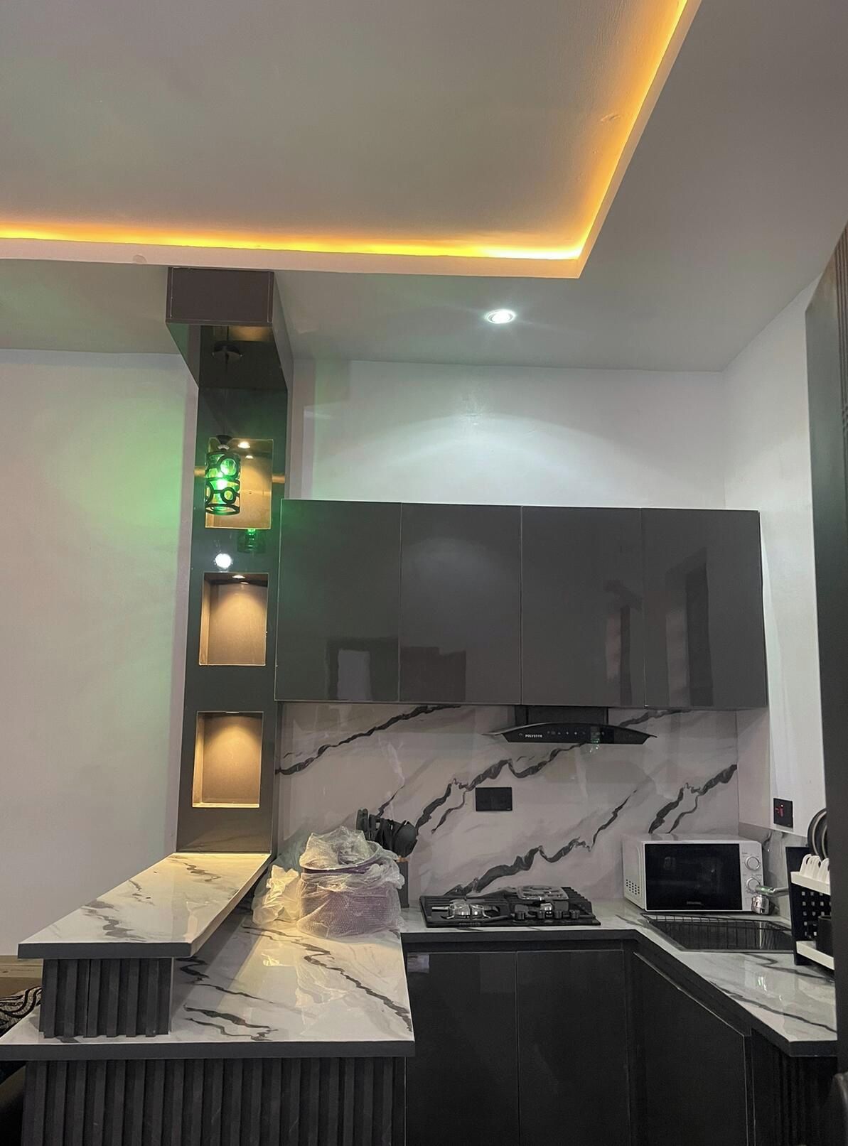 A modern kitchen with a marble backsplash, built-in cabinets, and under-cabinet lighting.