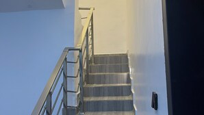 Un escalier avec des rampes en métal et des marches en bois menant à une porte de couleur sombre.