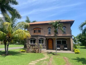 A two-story house with a stone facade, a wooden front door, and a balcony.