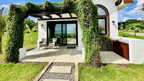A modern house with a covered patio, outdoor seating, and a large glass door. - 2BR Eco-Tiny Home Near the Beach by Veritas Pacifica • T4 (Gran Pacifica Resort)