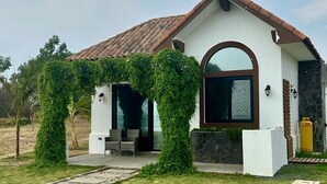 A modern house with a tiled roof, a covered patio, and a stone wall. - 2BR Eco-Tiny Home Near the Beach by Veritas Pacifica • T4 (Gran Pacifica Resort)