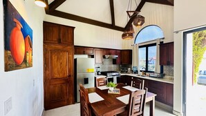 A spacious kitchen with wooden cabinets, a dining table, and a large window. - 2BR Eco-Tiny Home Near the Beach by Veritas Pacifica • T4 (Gran Pacifica Resort)