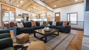 A spacious living area with a dark-colored sectional sofa, a wooden coffee table, and a rustic ceiling. - New Luxe at Laurel - Putting Green in Blue Ridge (Blue Ridge)