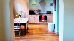 Une cuisine avec un plancher en bois, une table à manger avec des chaises et des placards.
