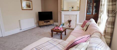 A living room with a sofa, a television, a fireplace, and a mirror.