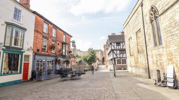 A cobblestone street lined with historic buildings, including a pub with outdoor seating and a sign reading "MASTONS."