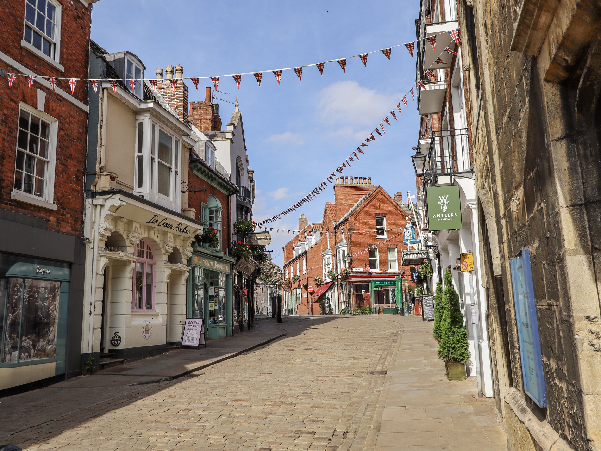 A cobblestone street lined with historic buildings, including a restaurant and a bar.