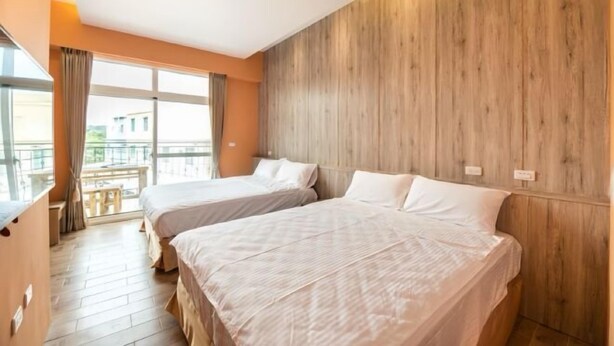Una camera d'albergo con due letti, pannelli di legno su una parete e un balcone con vista.