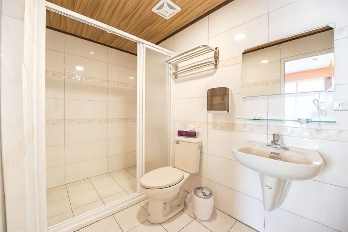 A bathroom with a shower, toilet, sink, and mirror.