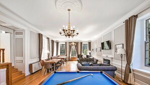 Une pièce spacieuse équipée d’une table de billard, d’un canapé, d’un coin repas et d’un lustre.