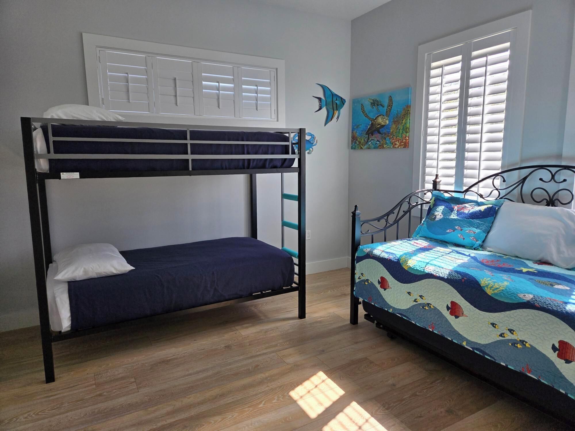 A room with a bunk bed, a single bed, and a window with blinds.
