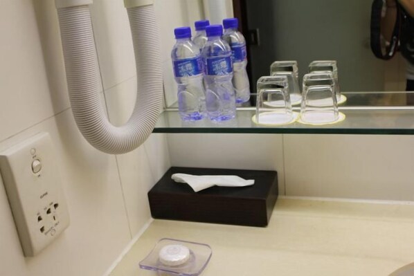 A bathroom with a glass shelf holding water bottles and glasses, a tissue box, and a soap dispenser. - Beijing Landmark Hotel (Beijing)