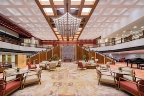 Un hall d’entrée spacieux avec un plafond haut, de nombreux espaces de détente et un grand escalier.
