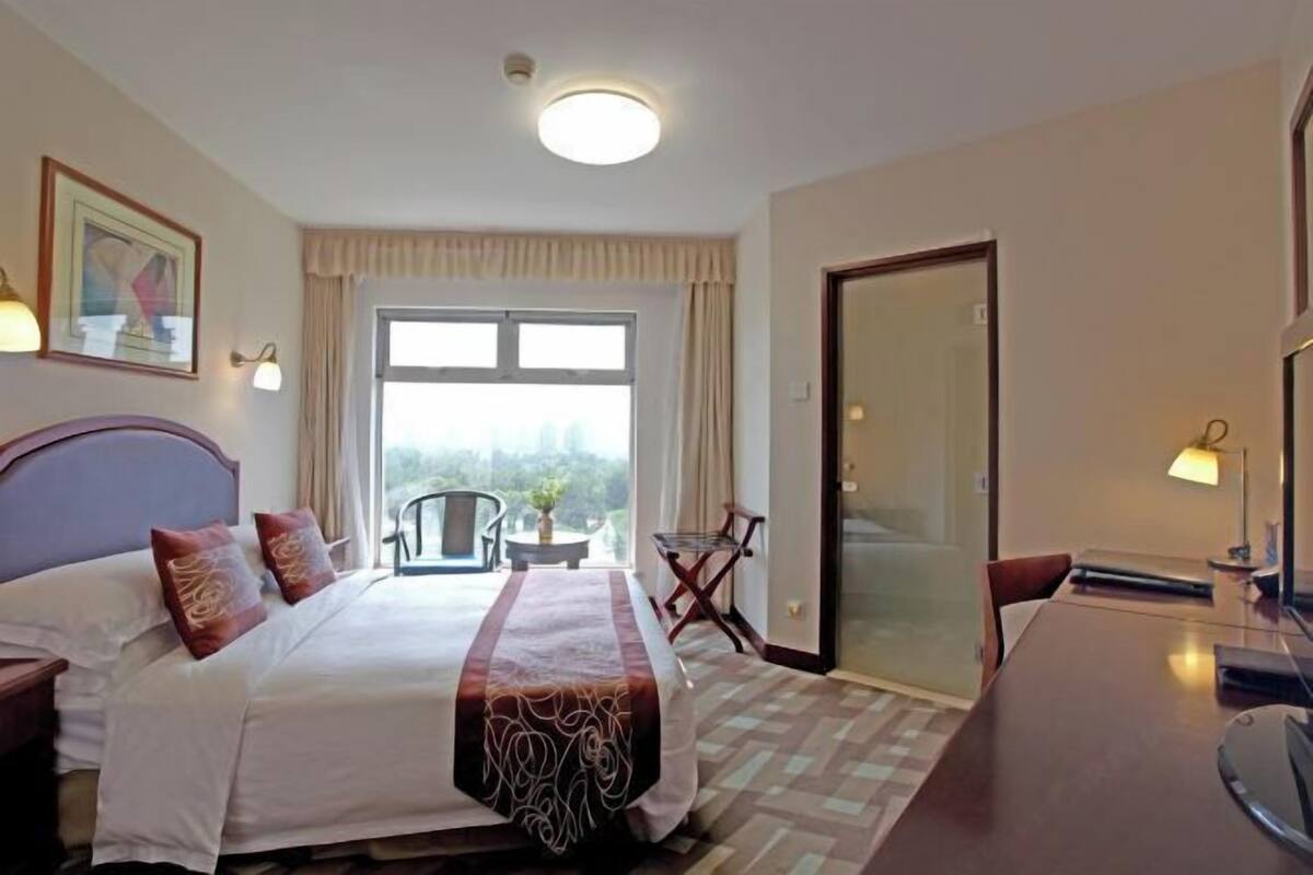 Una habitación de hotel con cama, escritorio, silla, ventana y puerta.
