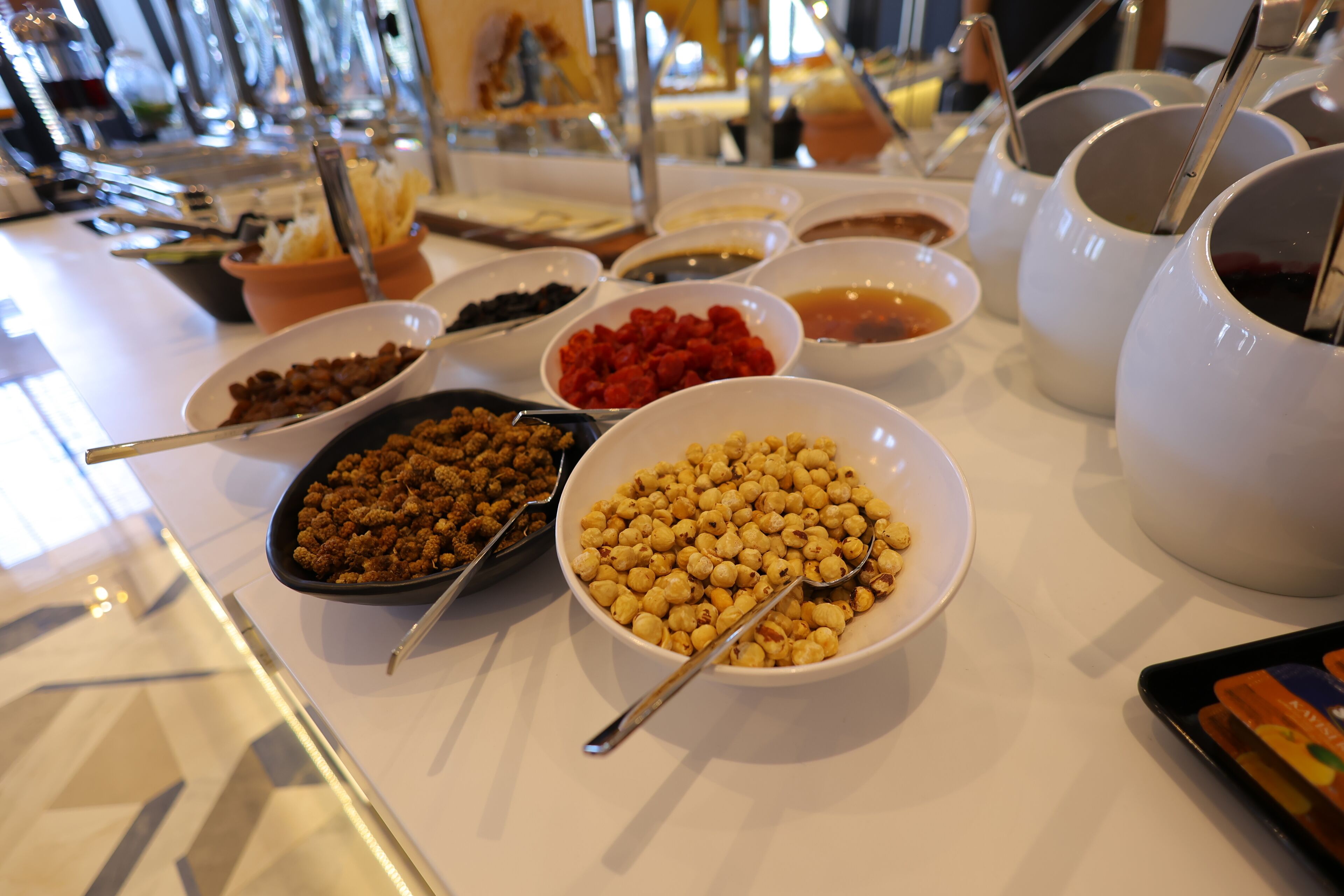 A buffet table with various food items and utensils.