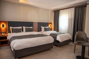 Quarto de hotel com duas camas, uma cadeira e uma mesa.
