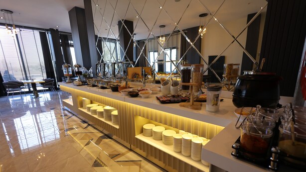 A buffet area with a variety of food items and beverages, a seating area with chairs, and a modern interior design. - Rest By Dedeman Elbistan (Elbistan)