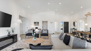 Una sala de estar moderna con un sofá, sillas, una mesa de centro y un televisor.