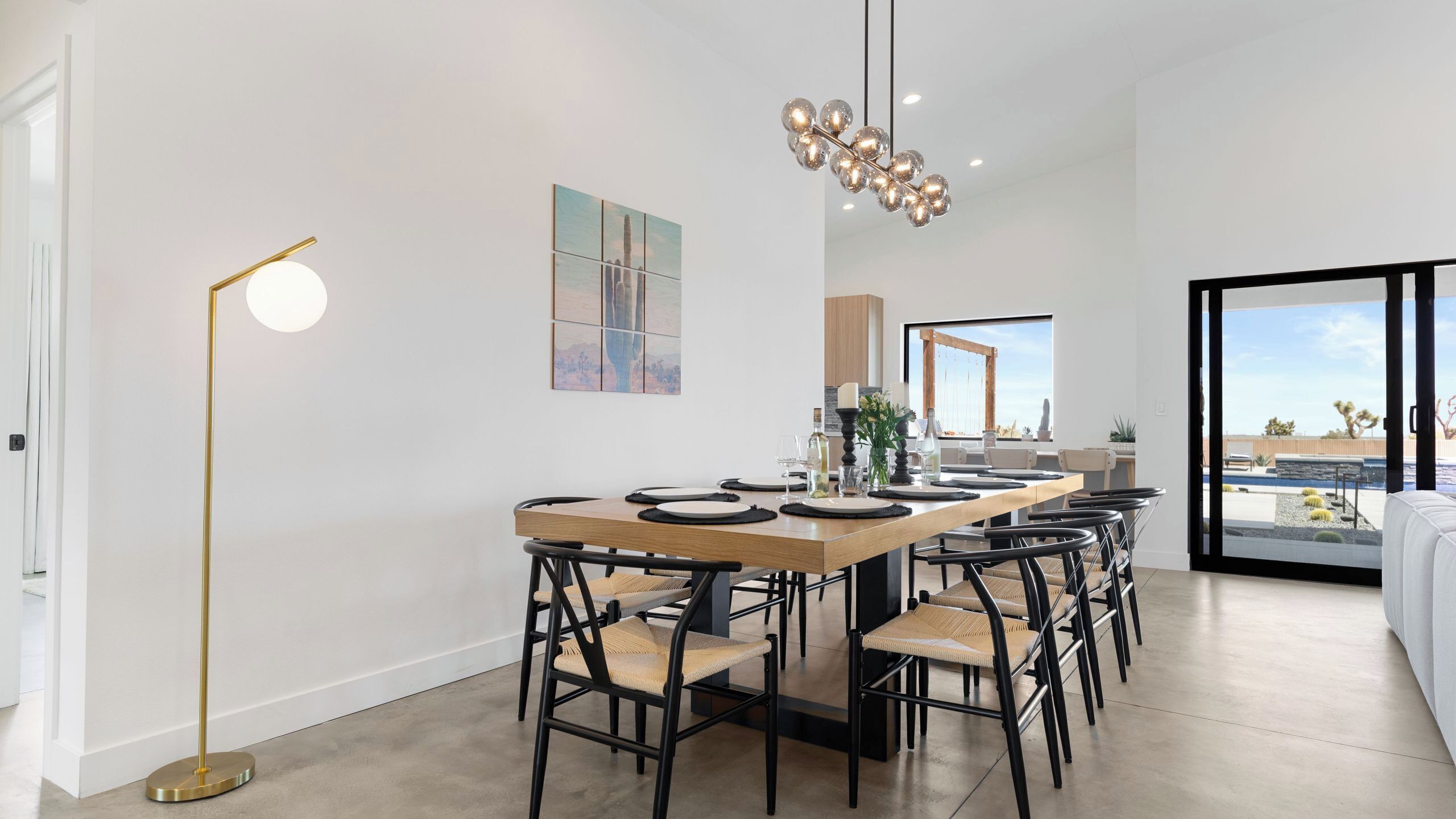 A modern dining area with a long table, black chairs, and a pendant light.