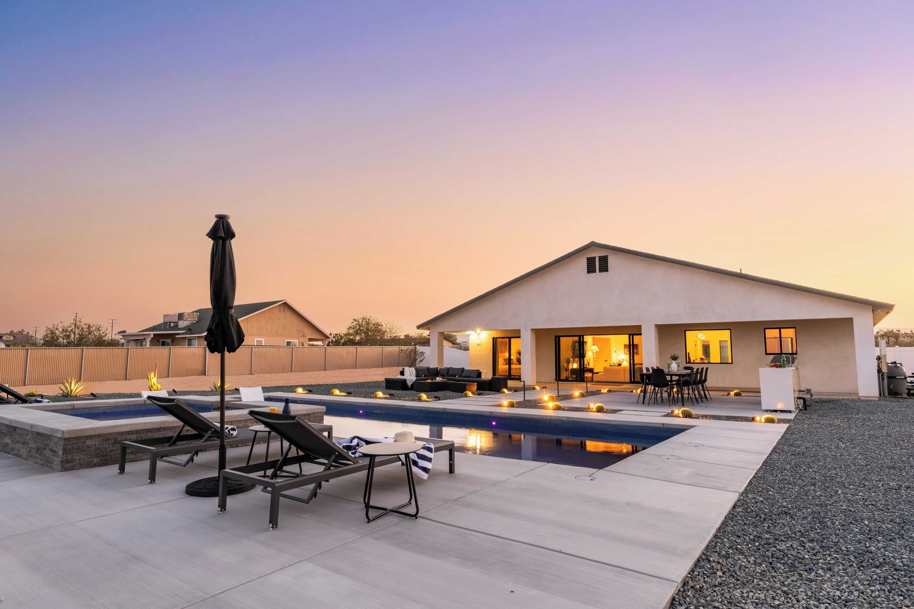 Une maison moderne dotée d’une piscine, d’un espace extérieur aménagé et d’un patio bien éclairé.