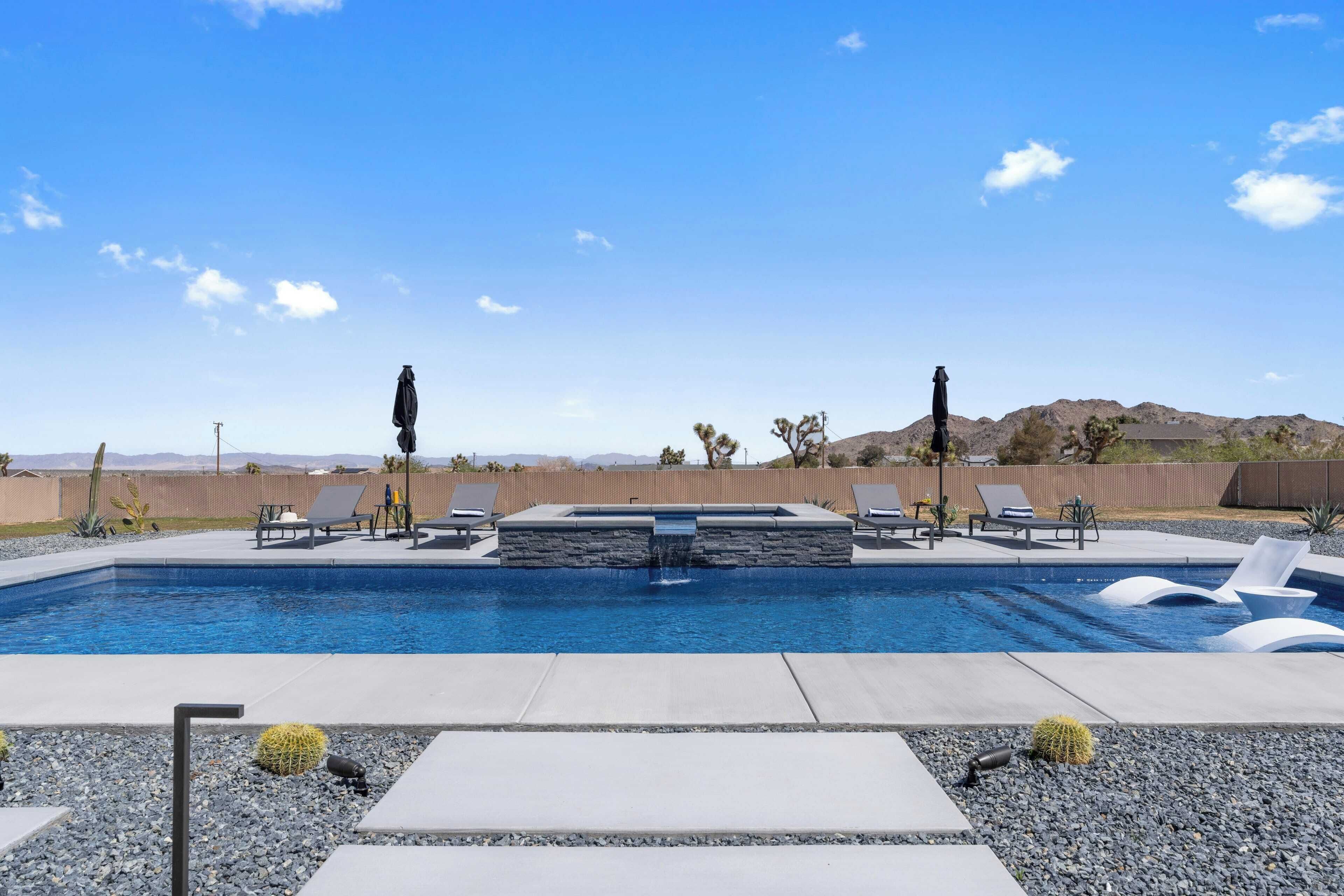 A swimming pool with lounge chairs and a waterfall feature.