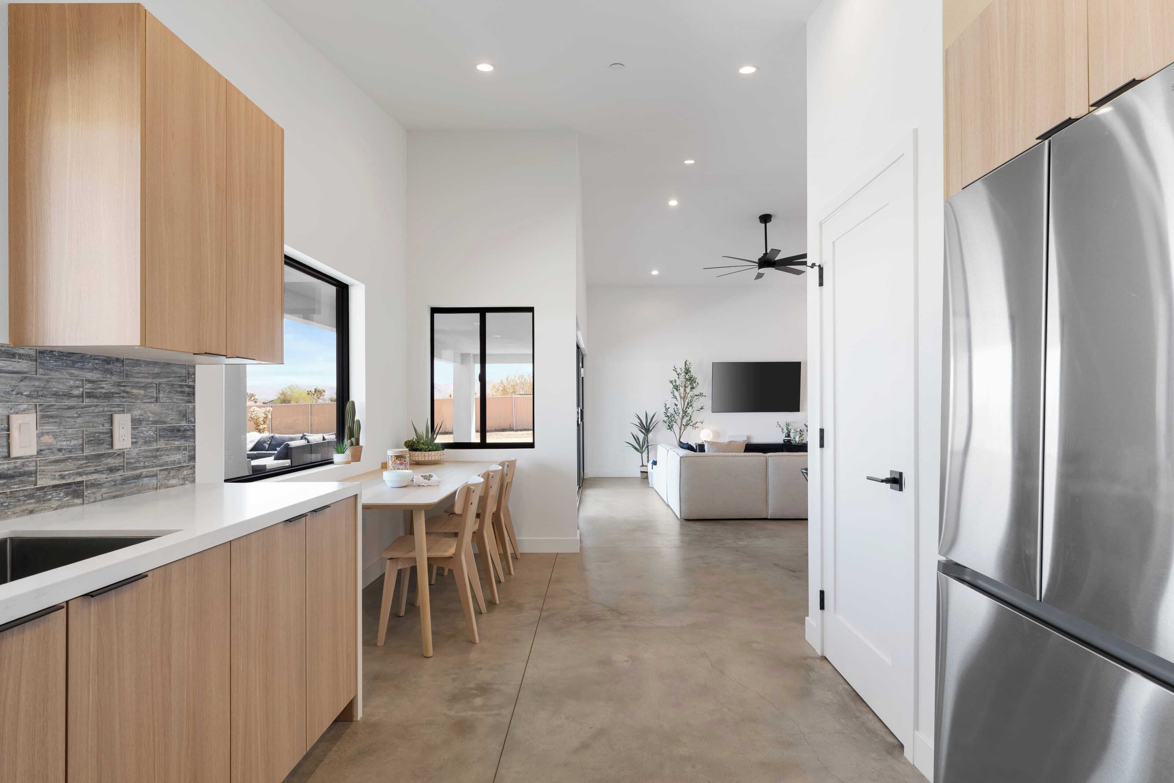 Una cocina moderna con armarios de madera, un refrigerador de acero inoxidable grande y un comedor con mesa y sillas.