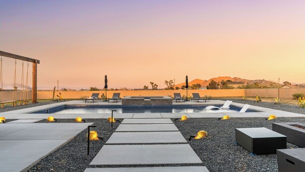 Un área de piscina en la azotea con sillones de descanso, una chimenea y vistas a montañas.