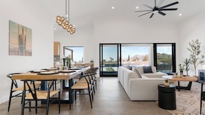 Una sala de estar moderna con comedor, ventanas amplias y vistas al exterior.