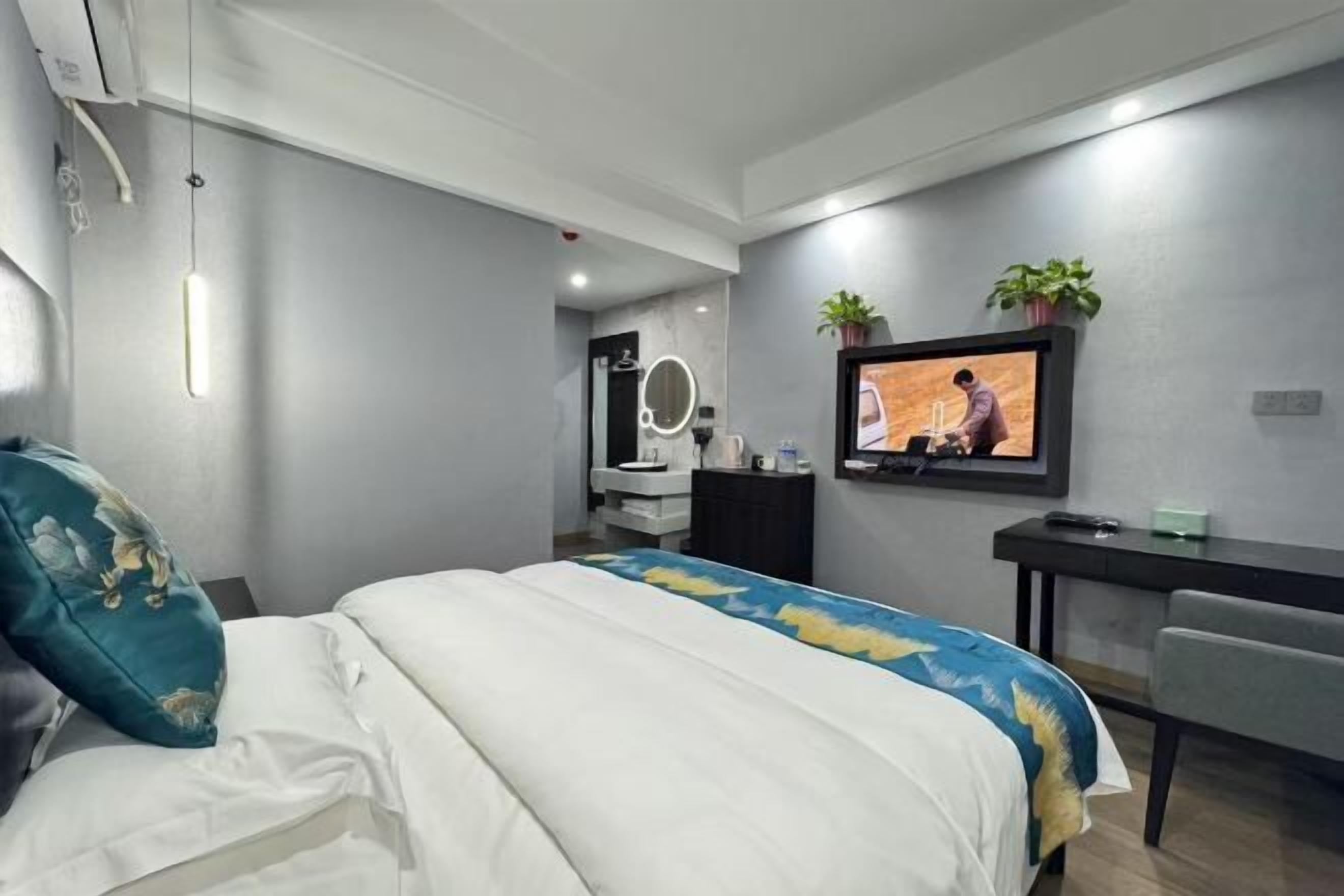 Una habitación de hotel moderna con una cama, un escritorio, un televisor y un baño al fondo.