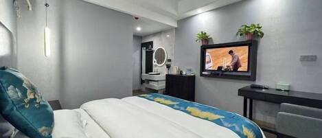 Una habitación de hotel moderna con una cama, un escritorio, un televisor y un baño al fondo.