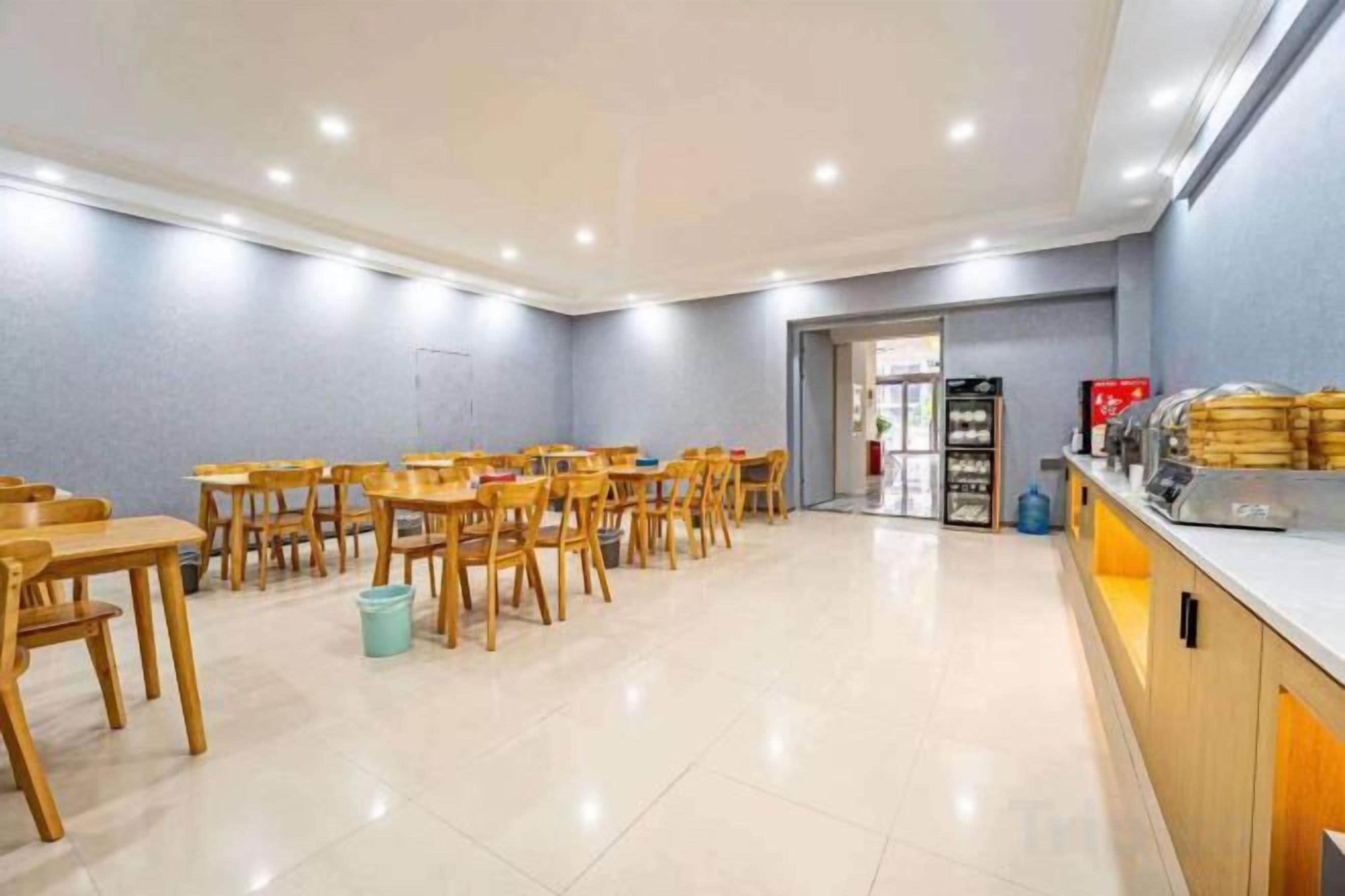 A dining area with multiple wooden tables and chairs, a counter with food items, and a tiled floor.