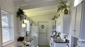 Ett modernt kök med vita skåp, ett matbord i glas och en avdelning för kaffebryggning.