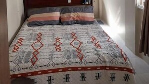 Una camera da letto con un letto, una testiera in legno, un comodino e una finestra con tende.