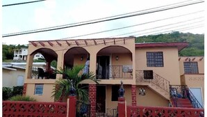 Un edificio a due piani con un balcone, una scala e un ingresso recintato.