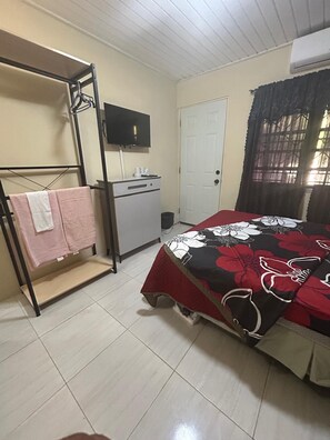 A bedroom with a bed, a desk, a television, a wardrobe, and a door. - Pelicans Nest Apartment (BirdRock)