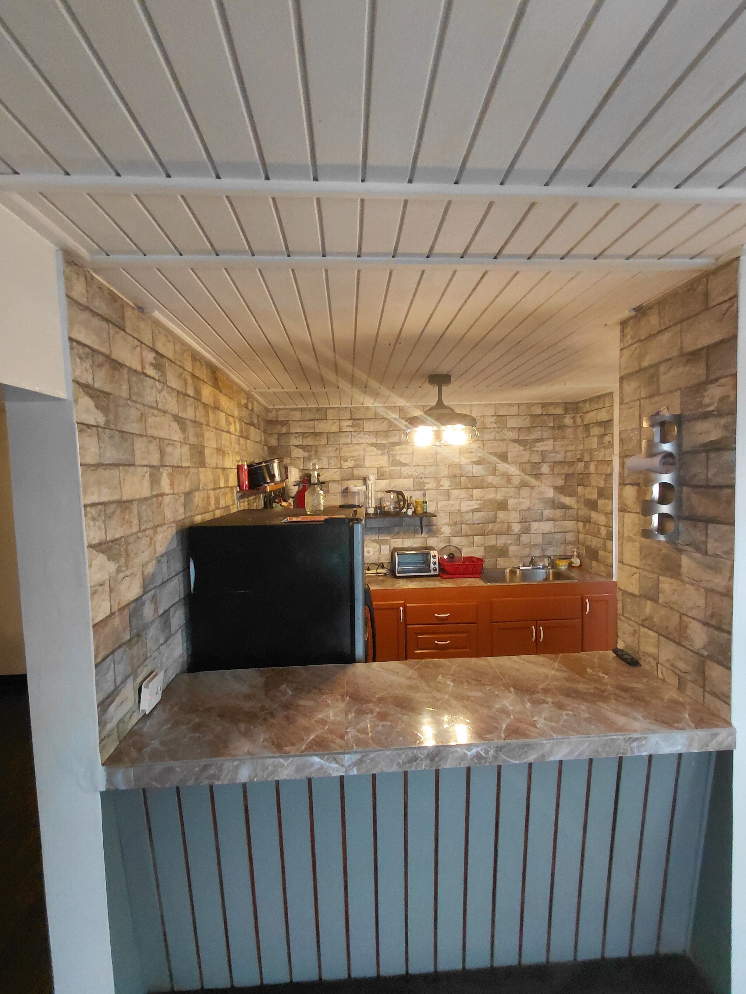 A compact kitchen with a stone backsplash, a built-in oven, a microwave, and a sink.