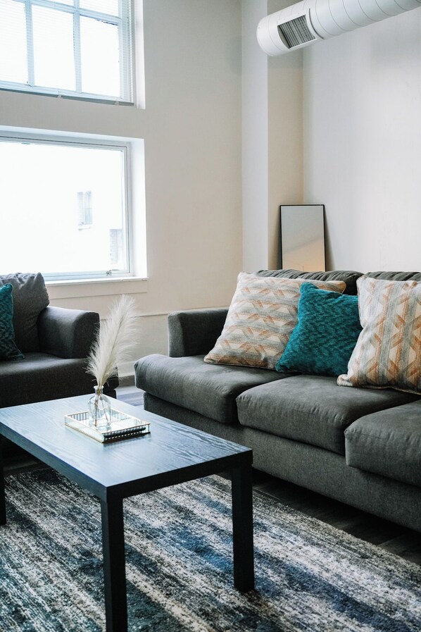 A modern living room with a grey sofa, a coffee table, and decorative pillows.