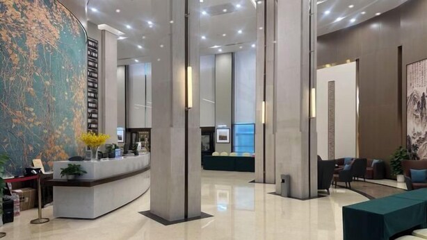 A modern lobby with a reception desk, seating area, and a large abstract mural. - Academic Exchange Center of Central China Normal University (Guiyuan Hotel) (Wuhan)