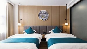 A hotel room with two beds, a wooden headboard, a wall-mounted artwork, and bedside lamps. - Academic Exchange Center of Central China Normal University (Guiyuan Hotel) (Wuhan)