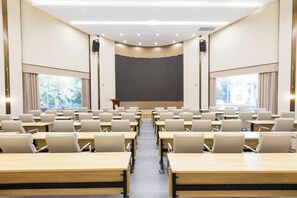A conference room with rows of tables and chairs, a podium, and a large screen at the front. - Academic Exchange Center of Central China Normal University (Guiyuan Hotel) (Wuhan)