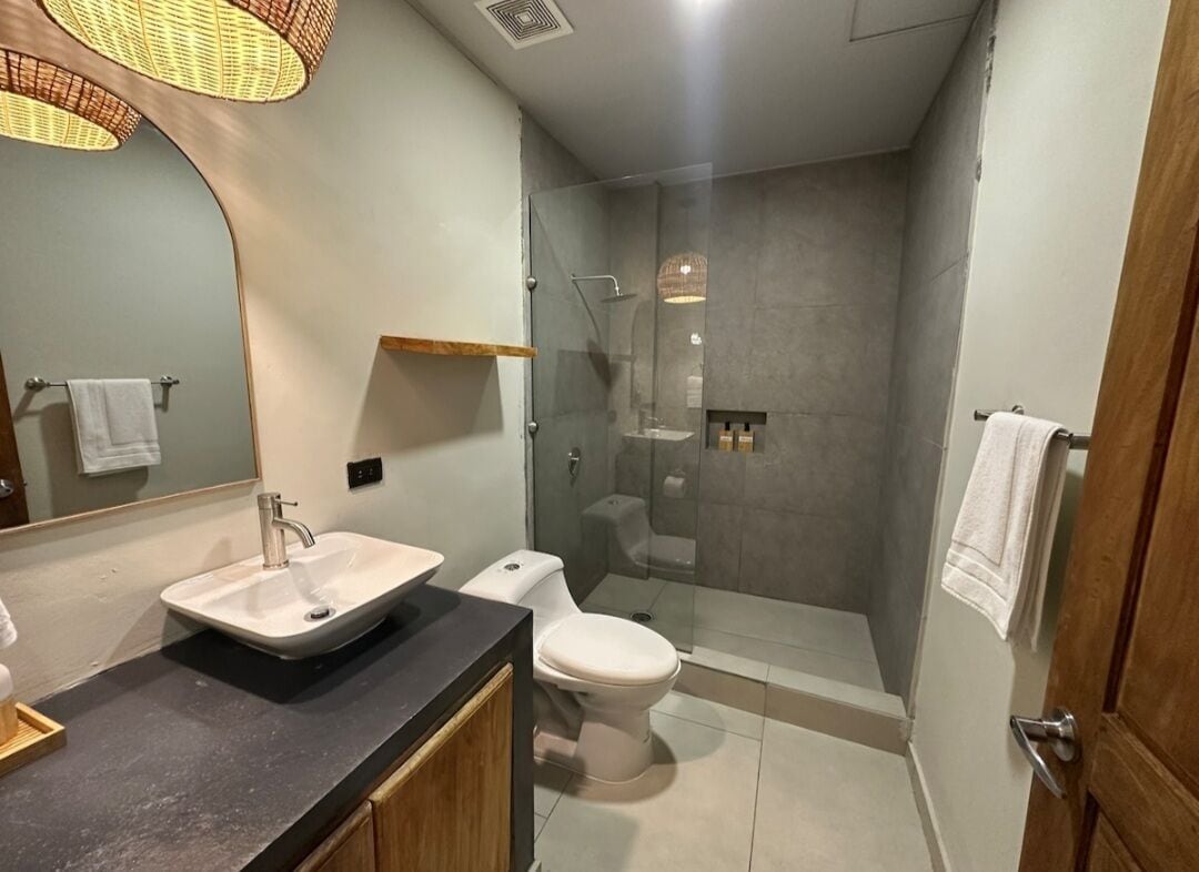 A modern bathroom with a sink, toilet, and glass-enclosed shower.