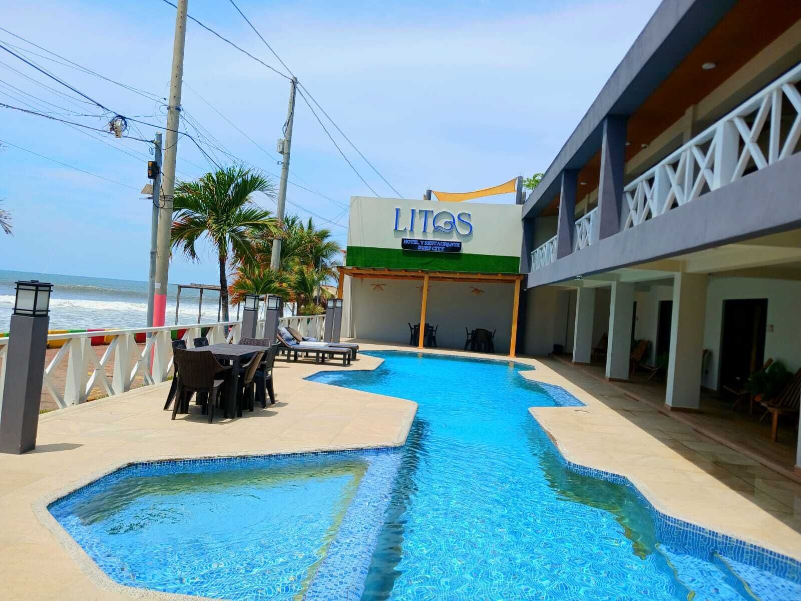 A hotel with a swimming pool, outdoor seating, and a view of the ocean.