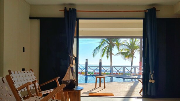Habitación con vista al mar, que incluye una silla de madera, una mesita y un banco junto a la piscina.