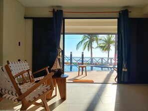 A room with a view of the sea, featuring a wooden chair, a small table, and a bench by the pool. - Litos Hotel y Restaurante (La Libertad)