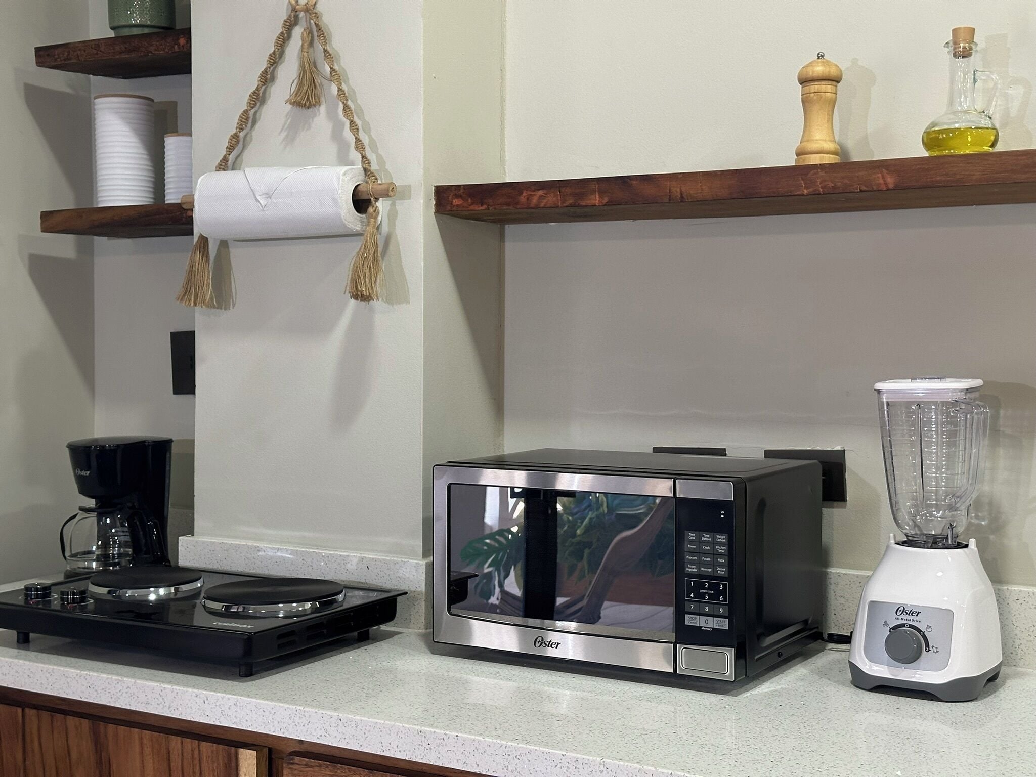 A kitchen with a microwave, a coffee maker, a blender, and shelves with kitchen items.