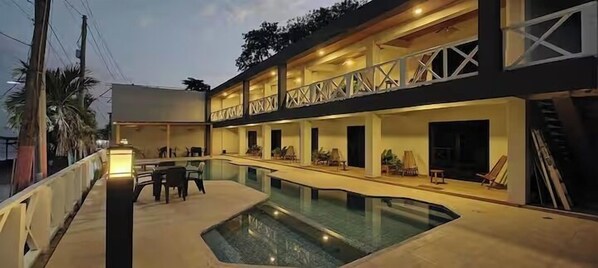 A modern hotel with a pool, outdoor seating, and a covered patio area. - Litos Hotel y Restaurante (La Libertad)
