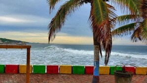 Vista costera con una mesa de madera y barreras coloridas, que da al mar y edificios distantes.