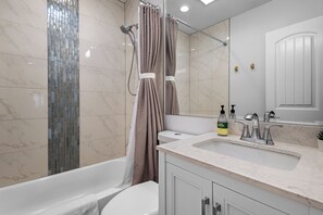 Ein modernes Badezimmer mit einer Badewanne, einer Dusche, einem Waschbecken mit Spiegel und einer Toilette.